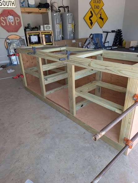 Wood cabinet base framing clamped together in a garage workshop