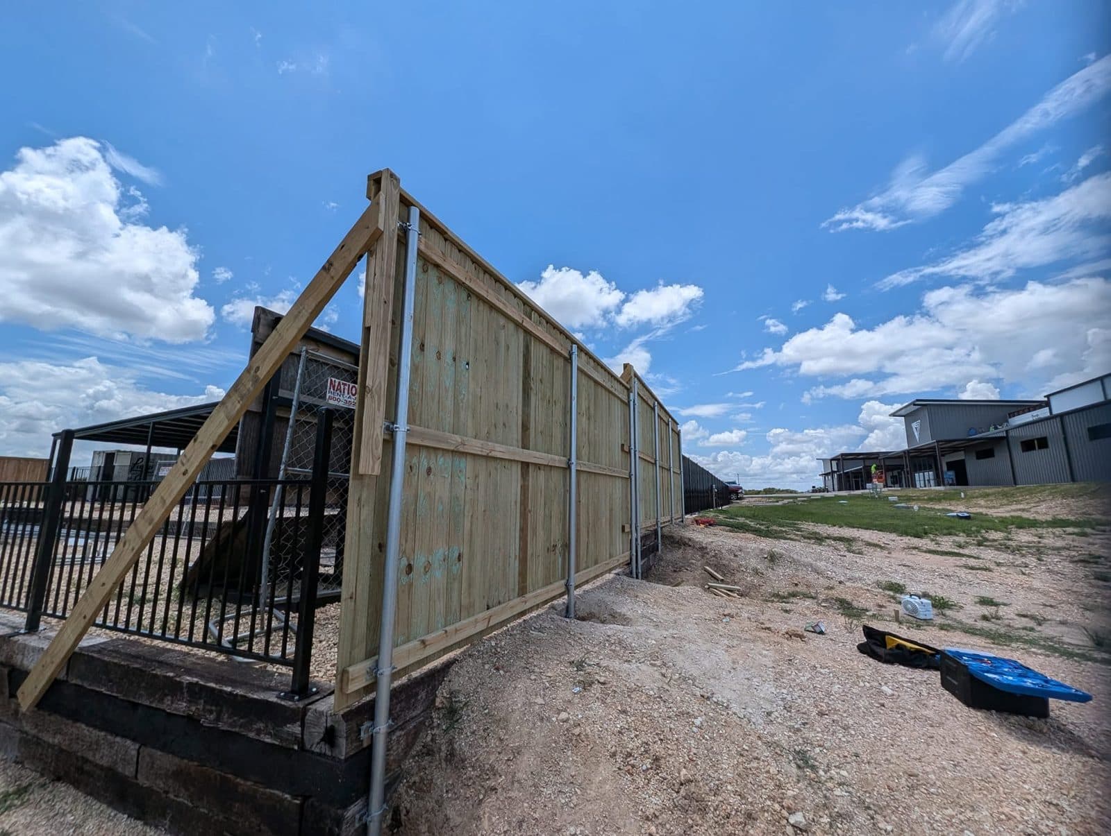 Fence end braced during the build, with steel posts set along the grade