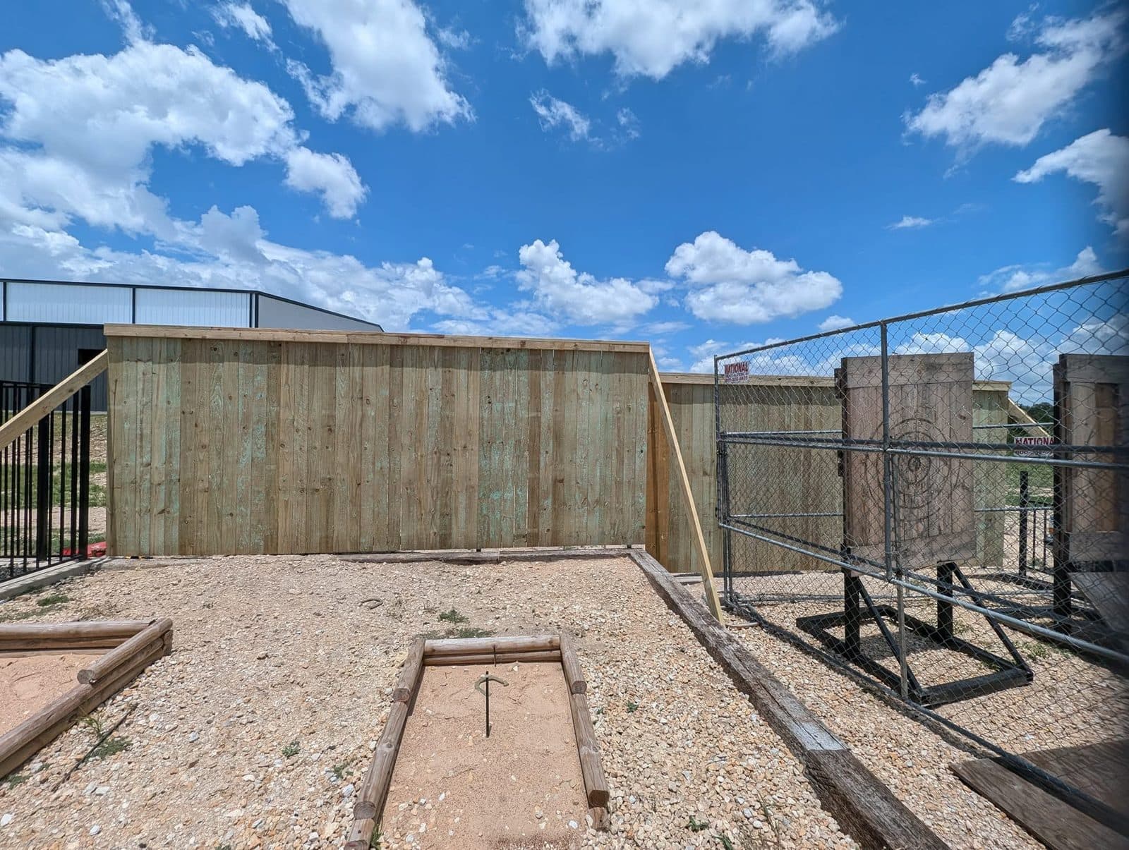 The new privacy fence closing in a gravel yard behind a metal building