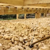 River rock being spread beneath the deck framing