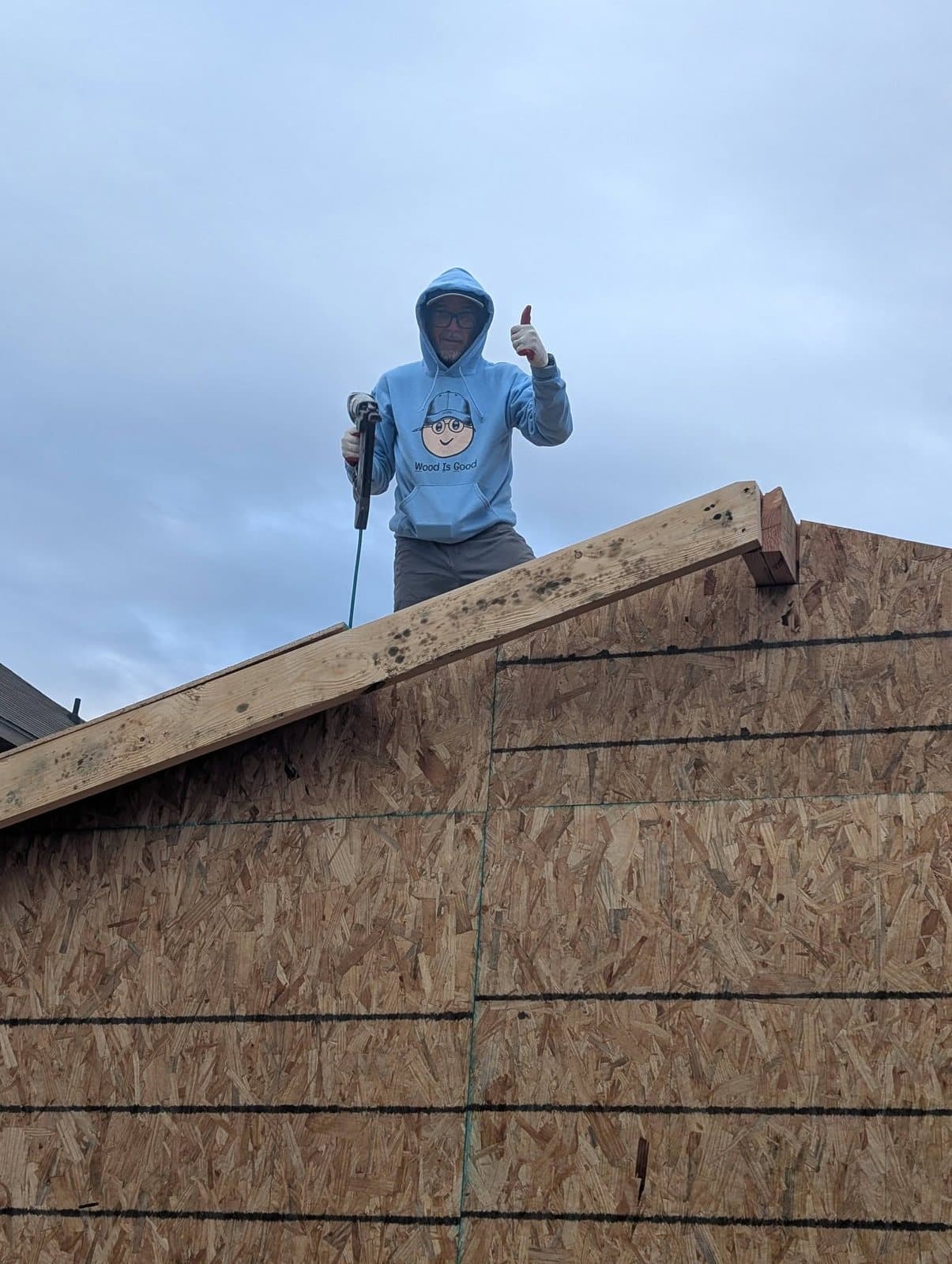 JT on top of the shed during framing, giving a thumbs-up