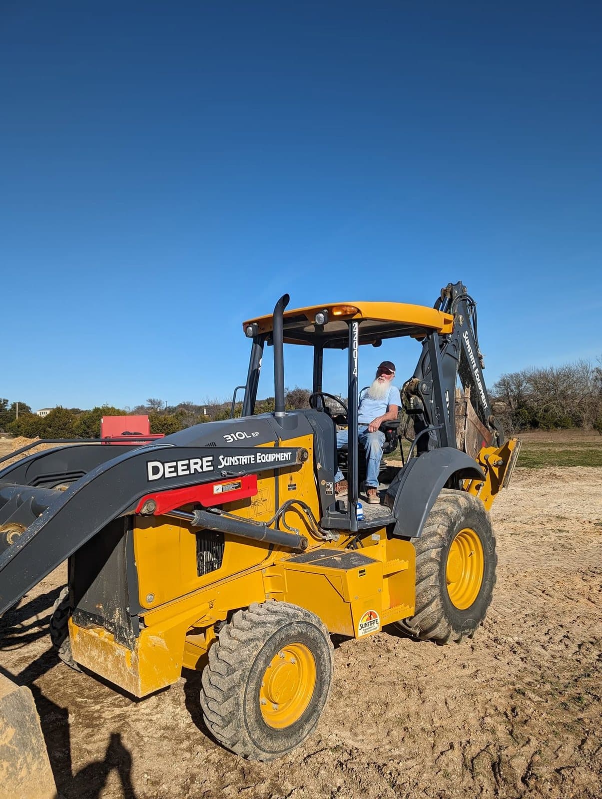 Crew member at the controls of a backhoe on the job site