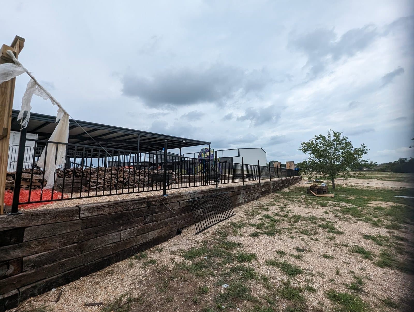 Long finished timber retaining wall with French drain grates along the gravel walkway