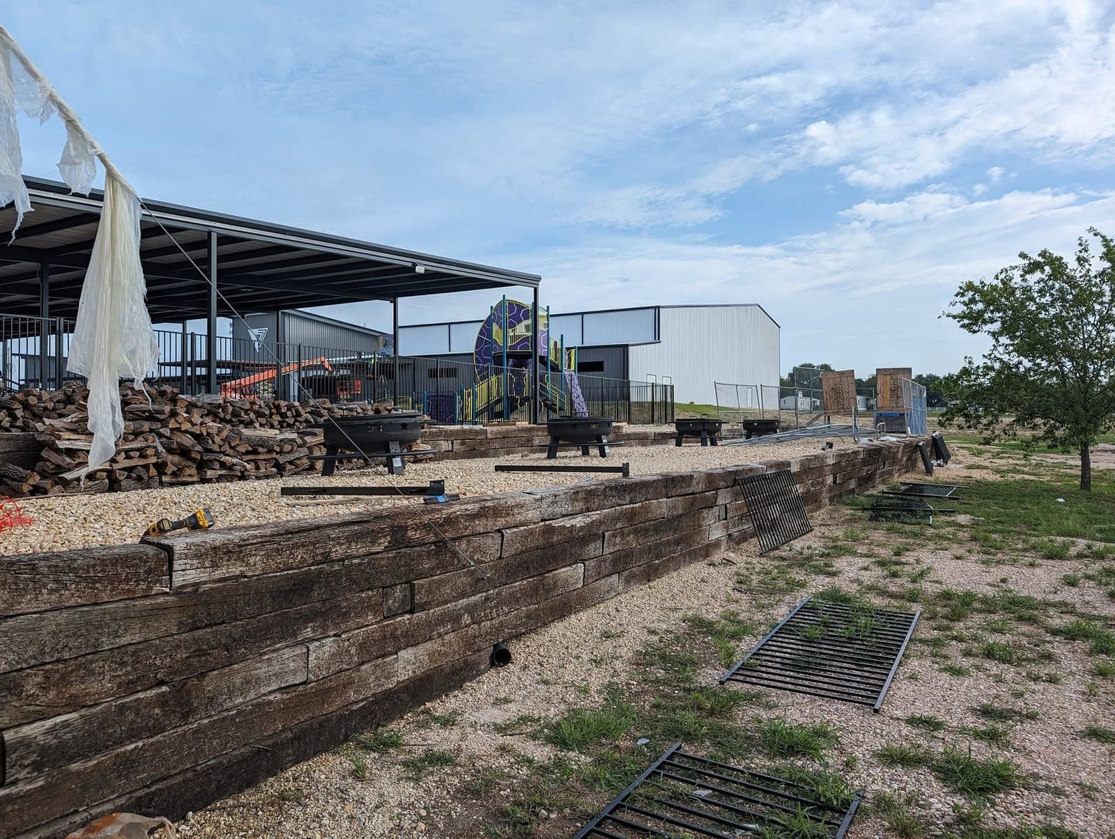 Finished terraced timber retaining walls with drain grates set into the gravel, below a covered pavilion