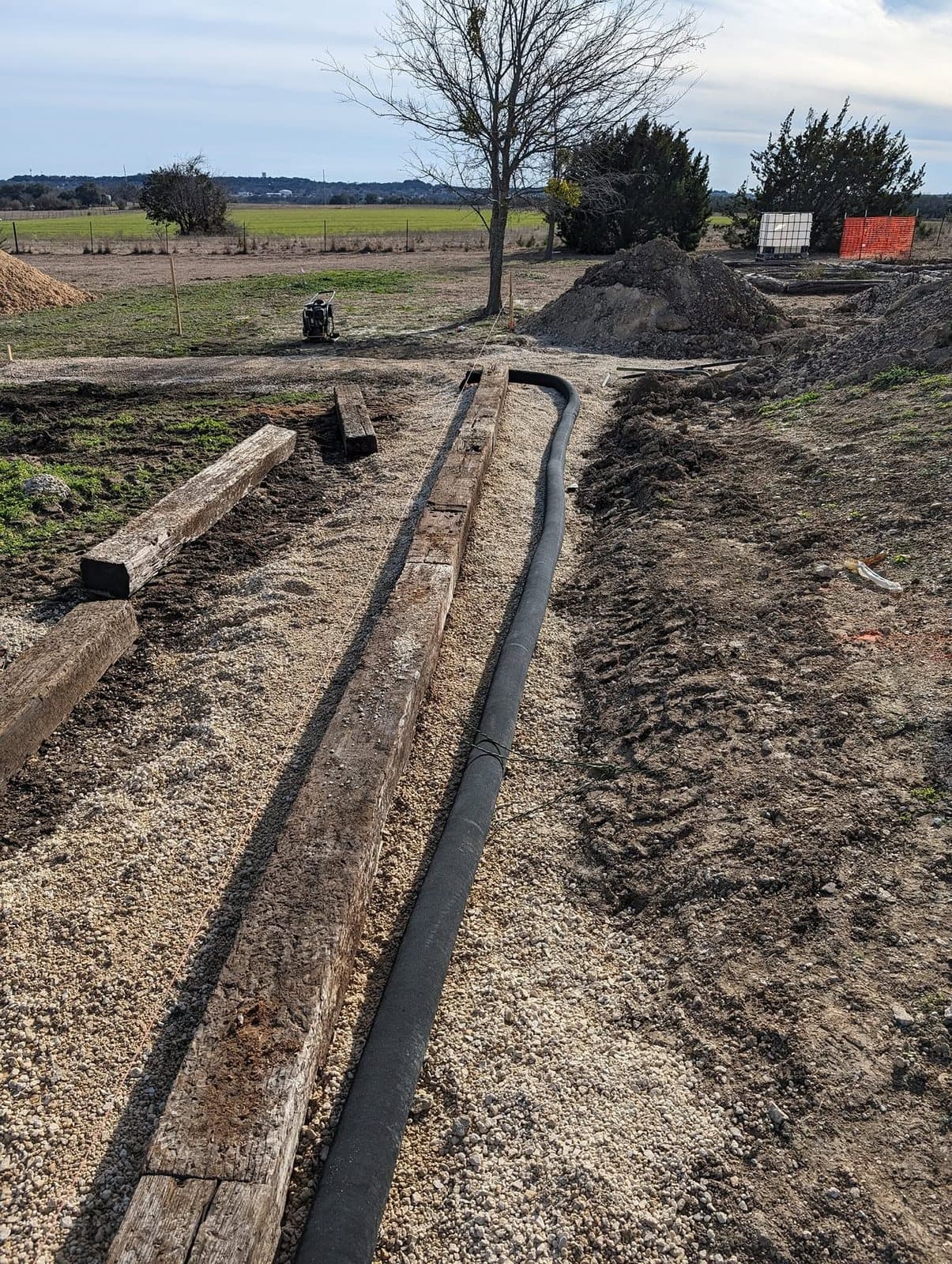 Perforated French drain pipe laid in gravel directly behind the first course of timbers